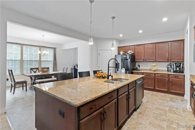 kitchen with dishwasher, sink, black fridge, light stone counters, and an island with sink