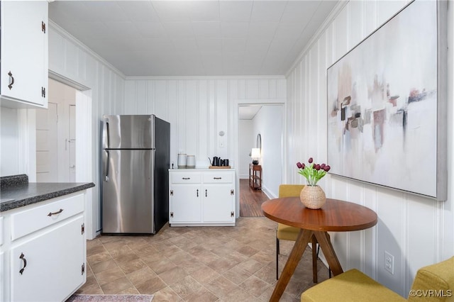 kitchen featuring white cabinets, ornamental molding, and stainless steel refrigerator