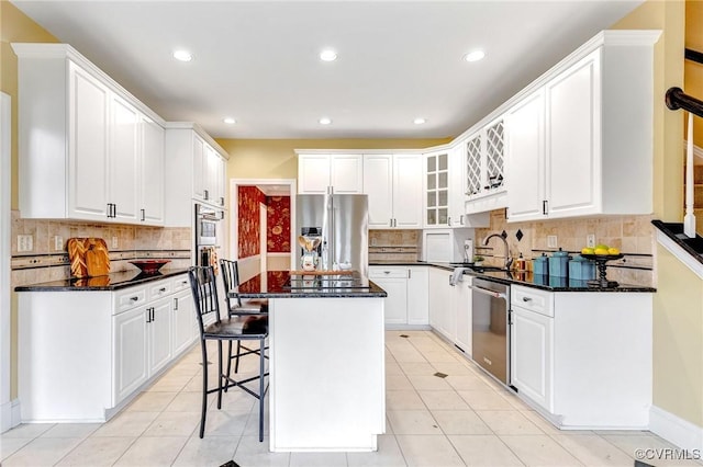 kitchen featuring decorative backsplash, a center island, white cabinets, and appliances with stainless steel finishes