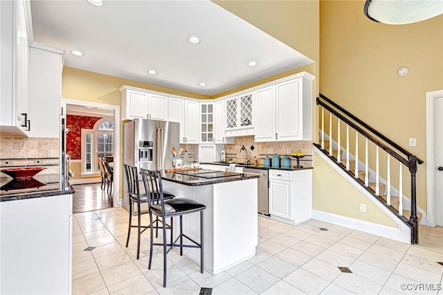 kitchen featuring tasteful backsplash, white cabinetry, a breakfast bar, and a kitchen island