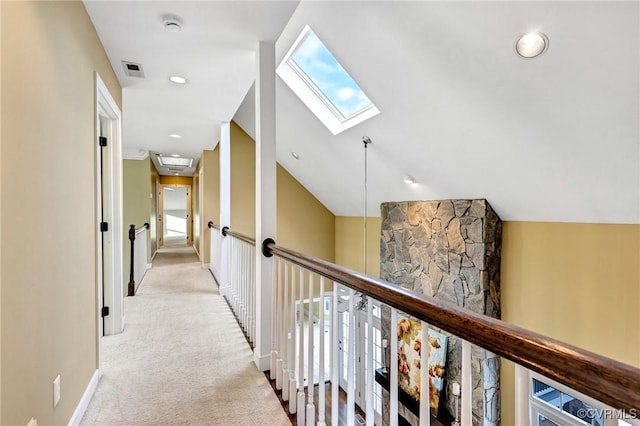 corridor with lofted ceiling with skylight and light carpet