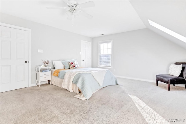 carpeted bedroom with ceiling fan and lofted ceiling with skylight