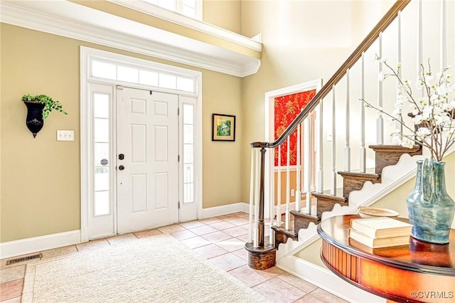 entrance foyer featuring crown molding and light tile patterned floors