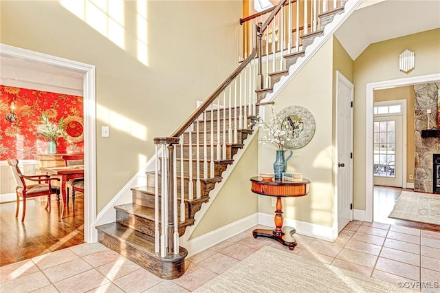 stairs with tile patterned floors and a stone fireplace