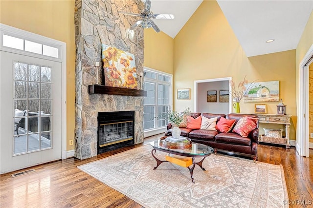 living room featuring ceiling fan, a fireplace, high vaulted ceiling, and wood-type flooring