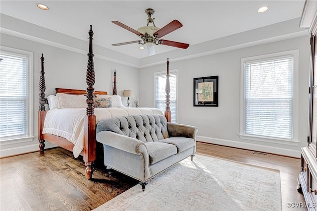 bedroom with hardwood / wood-style floors, ceiling fan, and multiple windows