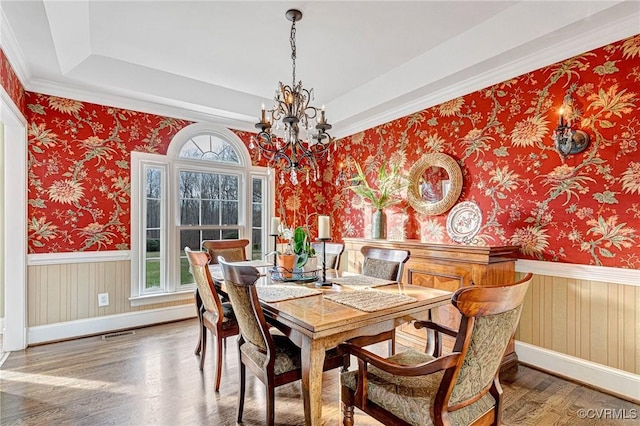 dining room featuring wood-type flooring, crown molding, and a chandelier