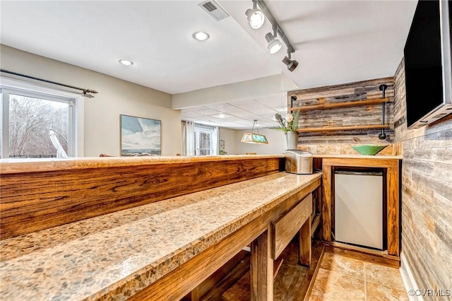 bar featuring light tile patterned floors, backsplash, and stainless steel refrigerator