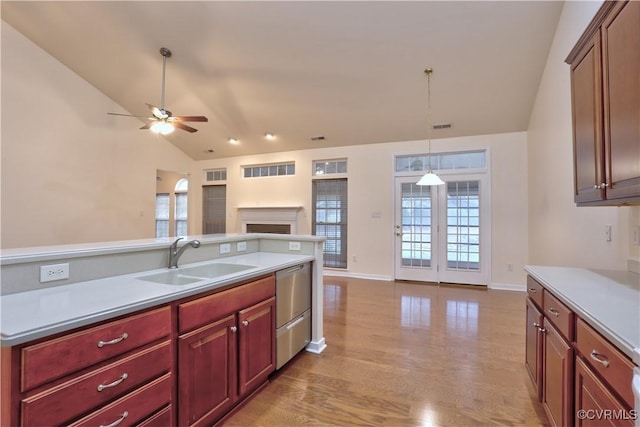 kitchen with sink, vaulted ceiling, ceiling fan, light wood-type flooring, and decorative light fixtures