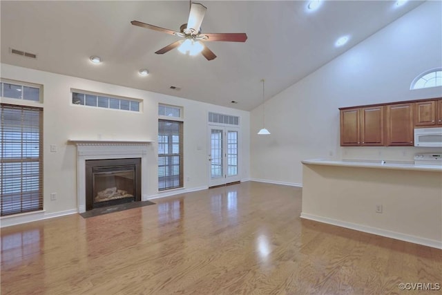 unfurnished living room with high vaulted ceiling, light hardwood / wood-style flooring, plenty of natural light, and ceiling fan