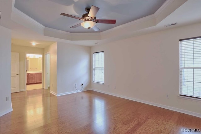 spare room with light hardwood / wood-style floors, a raised ceiling, and crown molding