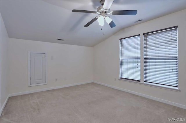 spare room featuring ceiling fan, light colored carpet, and vaulted ceiling