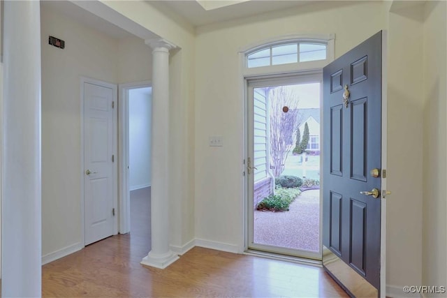 entrance foyer with ornate columns, a healthy amount of sunlight, and light hardwood / wood-style floors