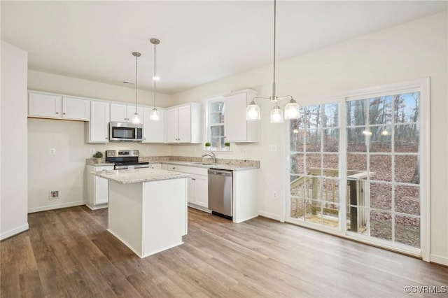 kitchen with a center island, white cabinets, hanging light fixtures, and appliances with stainless steel finishes