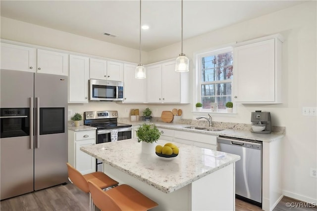 kitchen featuring white cabinets, sink, a kitchen island, wood-type flooring, and stainless steel appliances