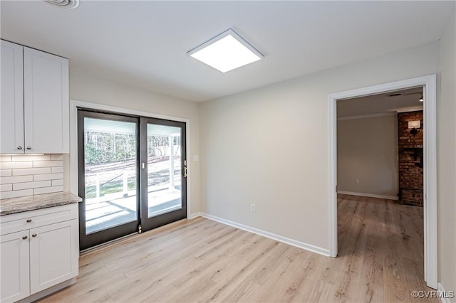 unfurnished dining area with light wood-type flooring and baseboards