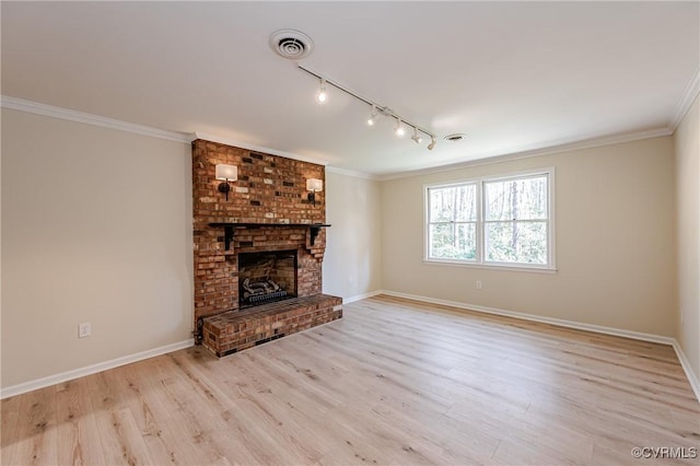 unfurnished living room with visible vents, light wood finished floors, baseboards, a fireplace, and crown molding