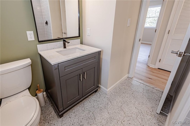 bathroom featuring baseboards, toilet, and vanity