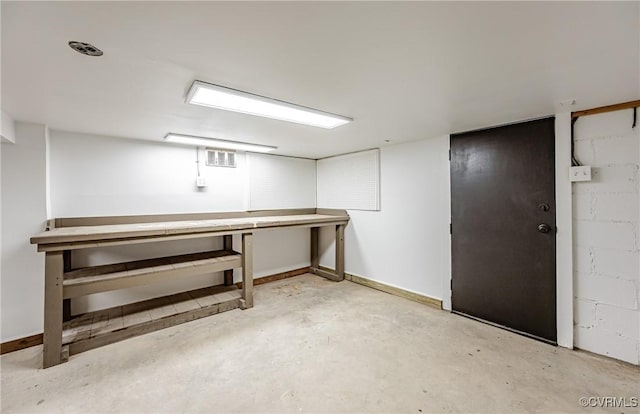 finished basement featuring visible vents, baseboards, and concrete block wall