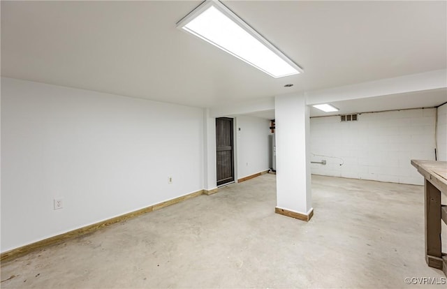 finished basement featuring concrete block wall, baseboards, and visible vents