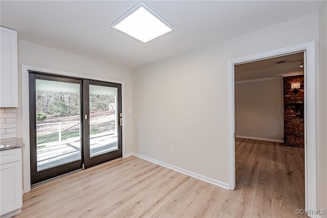 spare room featuring light wood-type flooring and baseboards