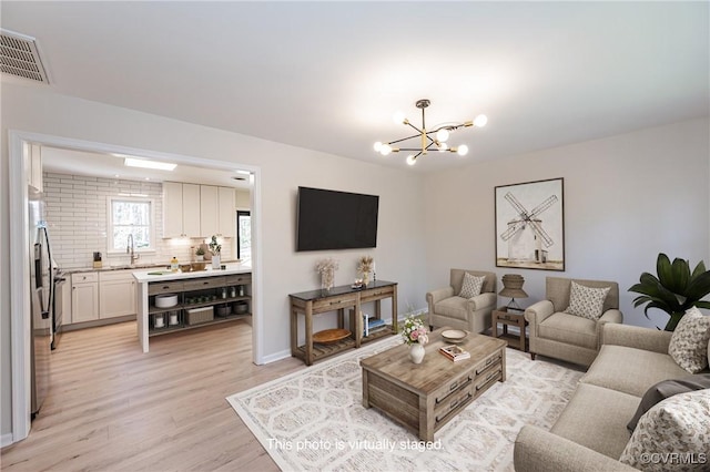 living room with a notable chandelier, visible vents, and light wood finished floors