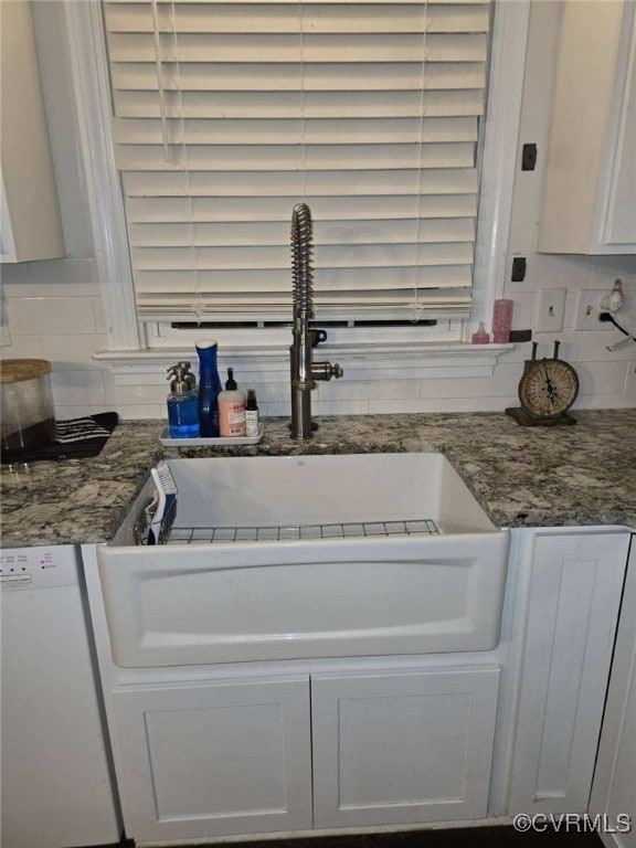 kitchen with white cabinetry, stone countertops, white dishwasher, and decorative backsplash