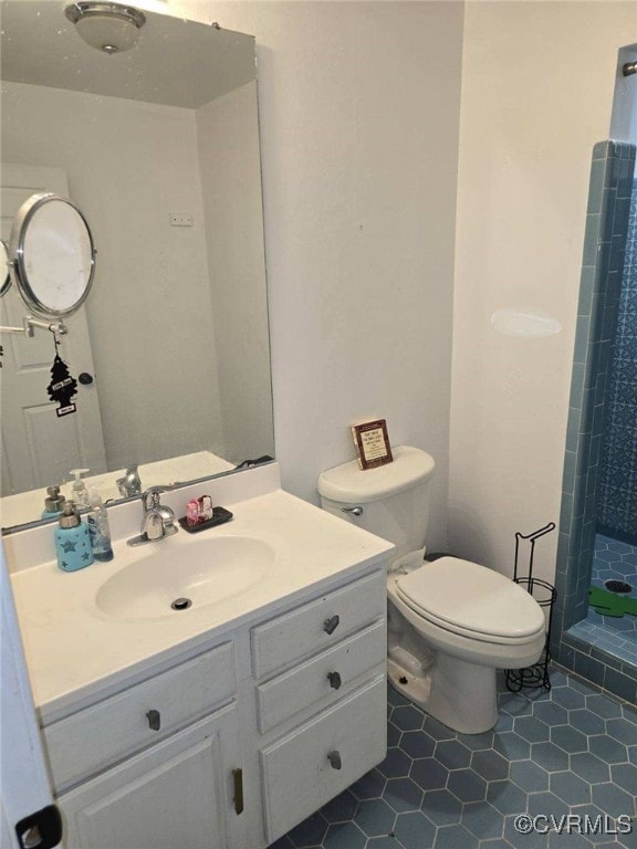 bathroom featuring tile patterned floors, vanity, toilet, and a tile shower