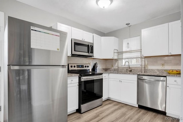 kitchen featuring stainless steel appliances, white cabinetry, light stone countertops, and hanging light fixtures