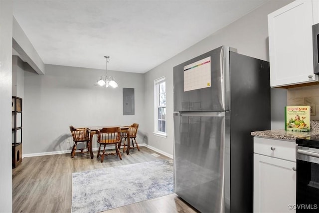 kitchen featuring light wood-type flooring, hanging light fixtures, electric panel, appliances with stainless steel finishes, and white cabinets