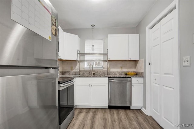 kitchen featuring white cabinetry, stainless steel appliances, and hanging light fixtures