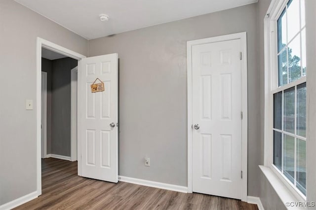 unfurnished bedroom featuring multiple windows and hardwood / wood-style floors