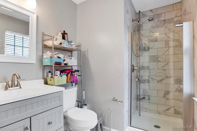 bathroom featuring toilet, vanity, and a shower with shower door