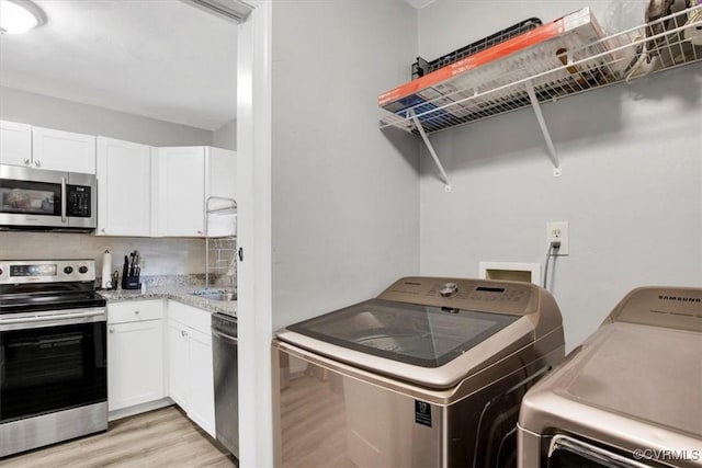 laundry room with independent washer and dryer and light hardwood / wood-style floors