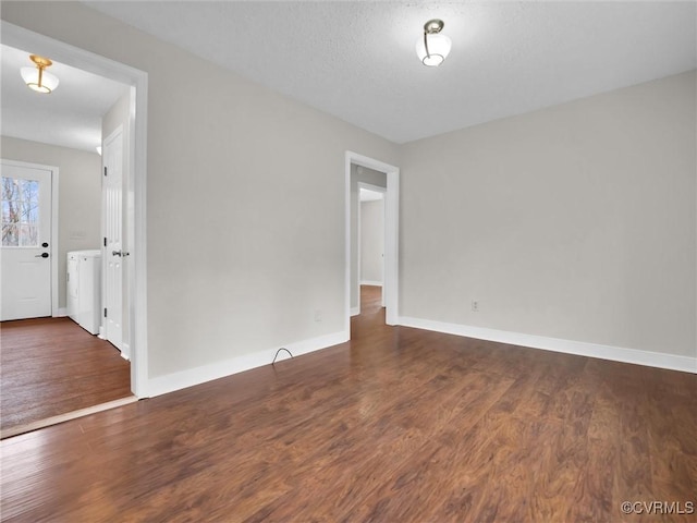 spare room with dark hardwood / wood-style flooring, a textured ceiling, and washer / dryer