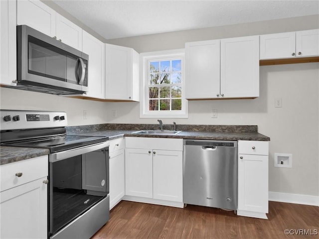 kitchen with dark hardwood / wood-style flooring, sink, white cabinetry, and stainless steel appliances