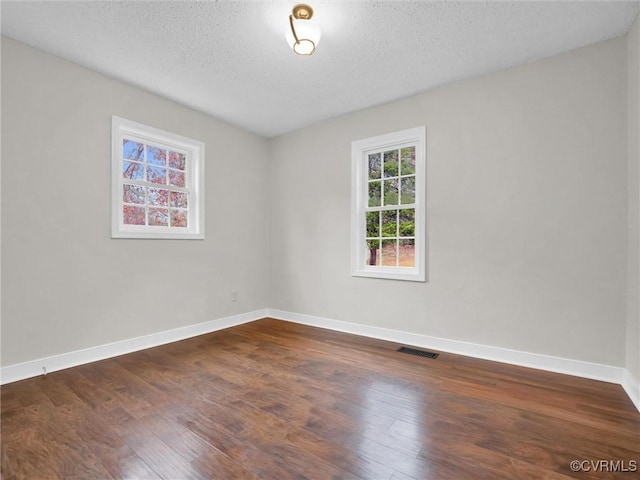 spare room with dark hardwood / wood-style flooring and a textured ceiling