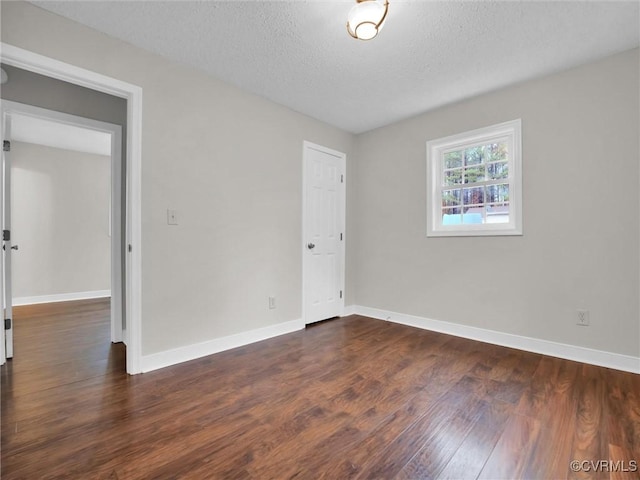 unfurnished room featuring dark wood-type flooring and a textured ceiling