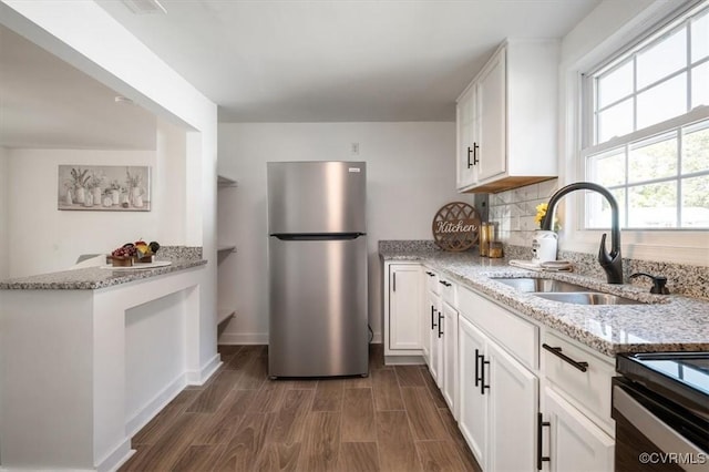 kitchen featuring white cabinets, light stone counters, sink, and stainless steel refrigerator