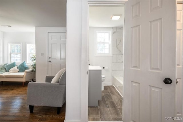 bathroom with shower / bath combination, hardwood / wood-style floors, a healthy amount of sunlight, and toilet