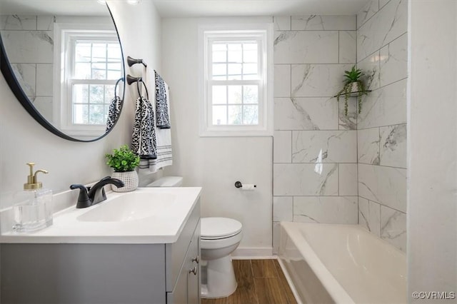 full bathroom featuring hardwood / wood-style floors, vanity, tiled shower / bath, and a wealth of natural light