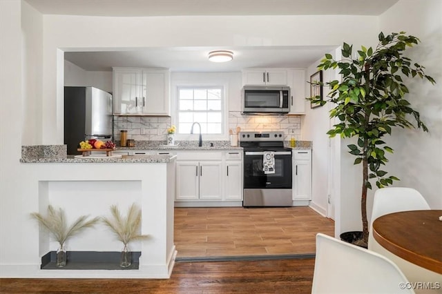 kitchen featuring white cabinetry, sink, light hardwood / wood-style flooring, backsplash, and appliances with stainless steel finishes