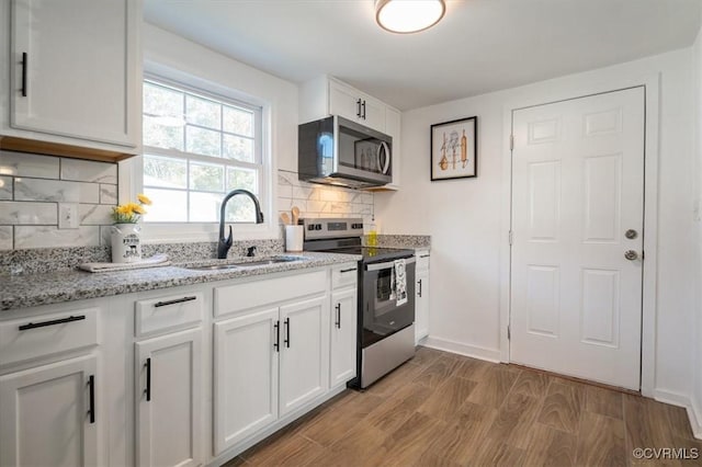 kitchen featuring sink, tasteful backsplash, light hardwood / wood-style floors, white cabinets, and appliances with stainless steel finishes