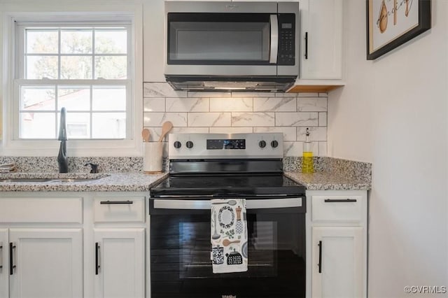 kitchen with white cabinetry, sink, stainless steel appliances, and light stone counters