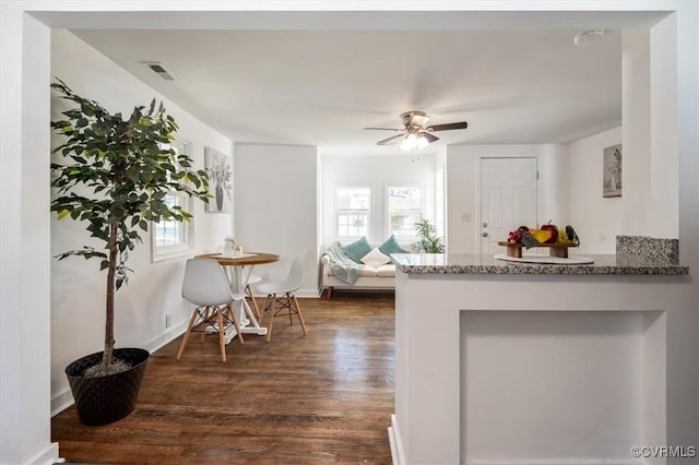 kitchen with ceiling fan, stone countertops, and dark hardwood / wood-style floors