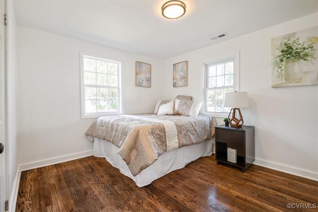 bedroom with dark wood-type flooring and multiple windows