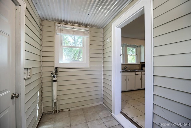 interior space featuring light tile patterned floors, sink, and wooden walls