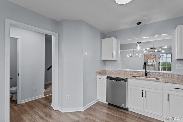 kitchen with stainless steel dishwasher, sink, hardwood / wood-style floors, white cabinetry, and hanging light fixtures