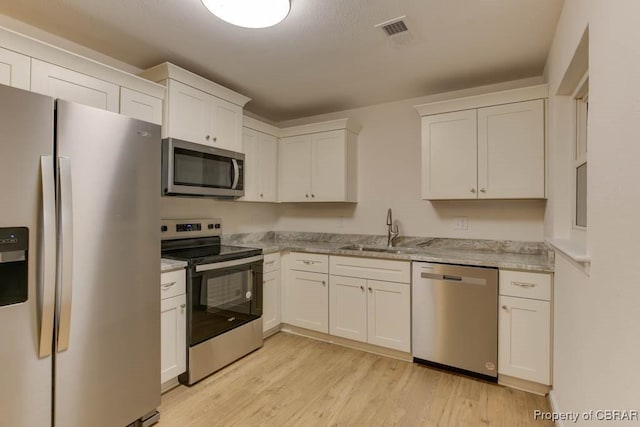 kitchen featuring white cabinets, light wood-type flooring, sink, and appliances with stainless steel finishes