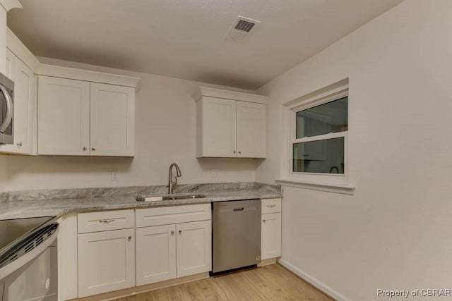 kitchen with light stone counters, stainless steel appliances, sink, white cabinets, and light hardwood / wood-style floors